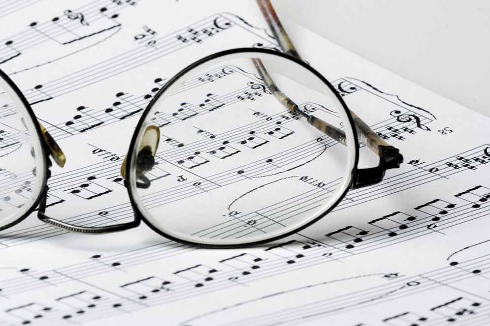 Restoration tools, manuscripts, and music sketches arranged on a wooden table