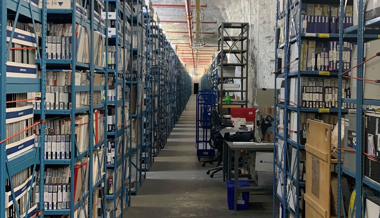 A dimly lit archival room with stacks of old sheet music and handwritten drafts